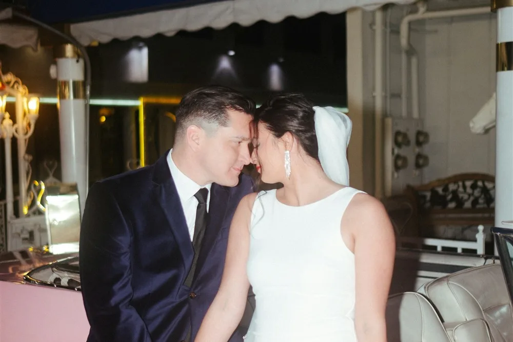 Casal de noivos em frente a um Cadillac cor-de-rosa em uma capela de casamento em Las Vegas