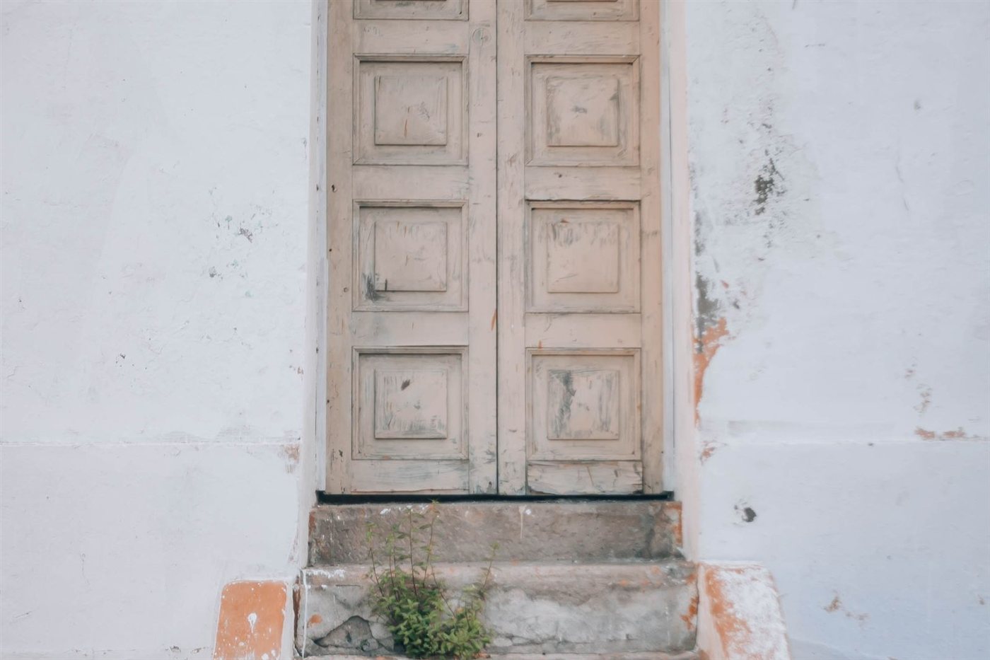 Porta de madeira desgastada em parede de pedra, típica das casas antigas do programa de 1 euro que ainda não passaram por reforma