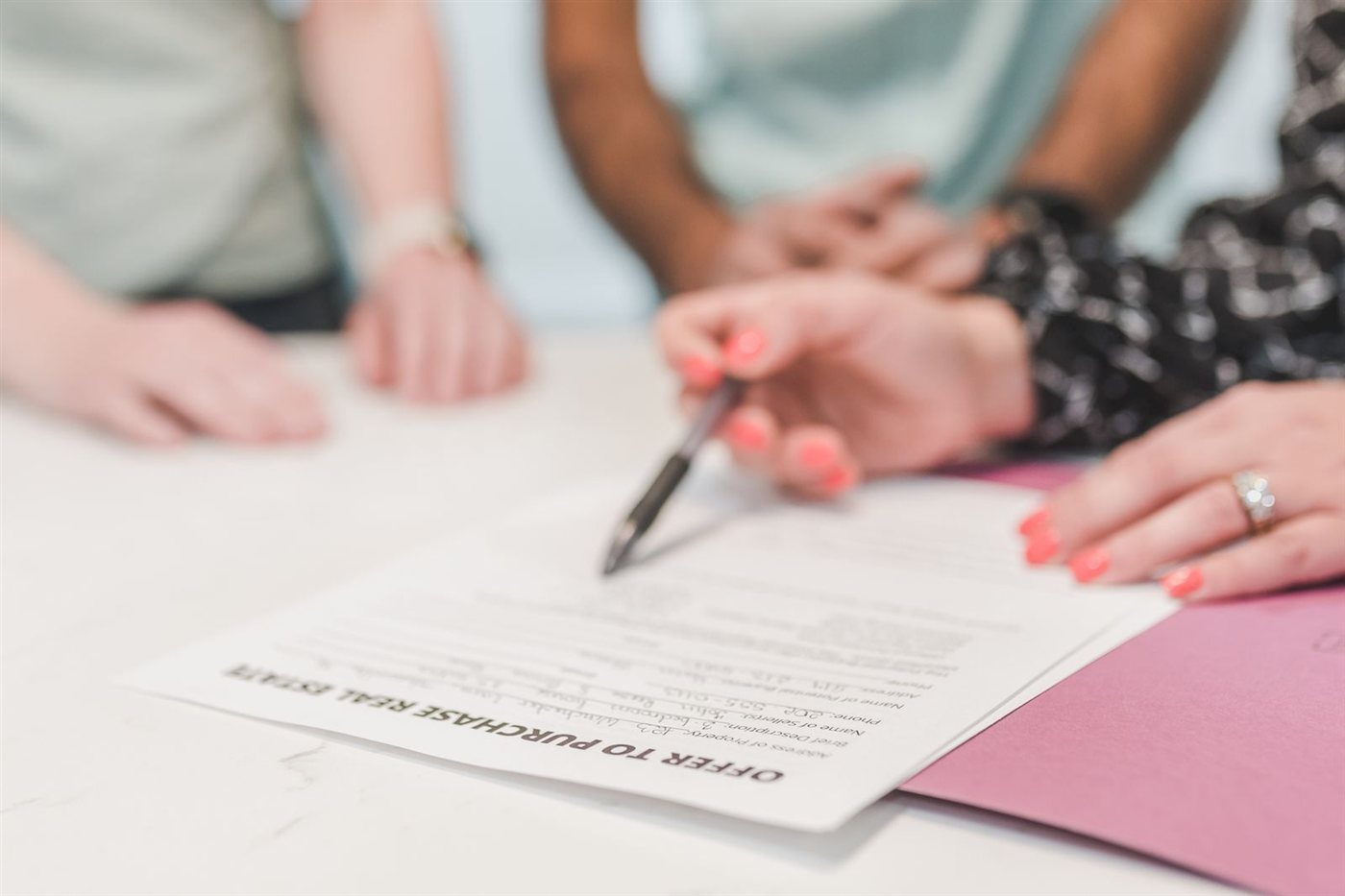 Duas pessoas assinando um contrato de compra de imóvel sobre uma mesa