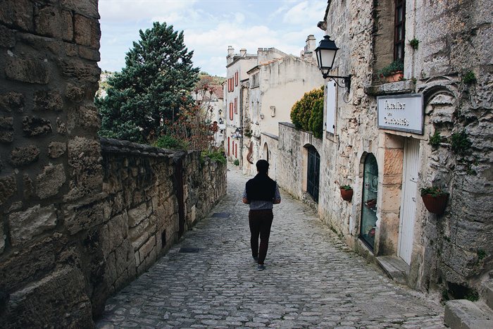 Pessoa caminhando por uma rua estreita de pedra em um vilarejo italiano antigo