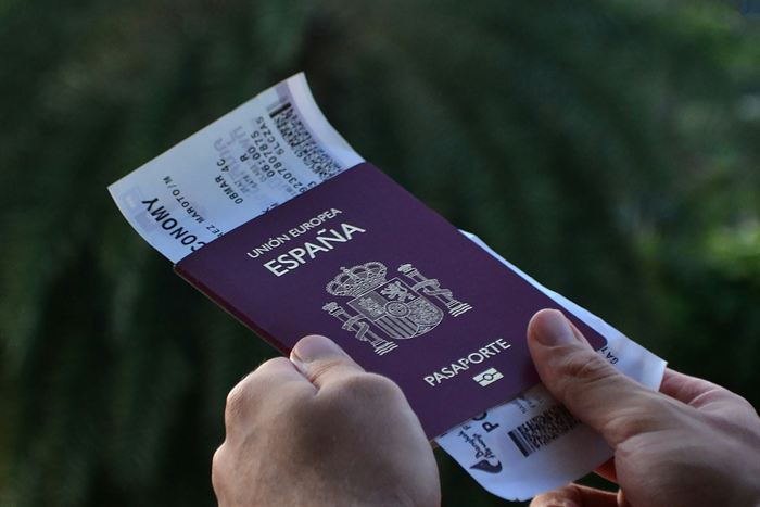 Mãos segurando um passaporte espanhol e um cartão de embarque