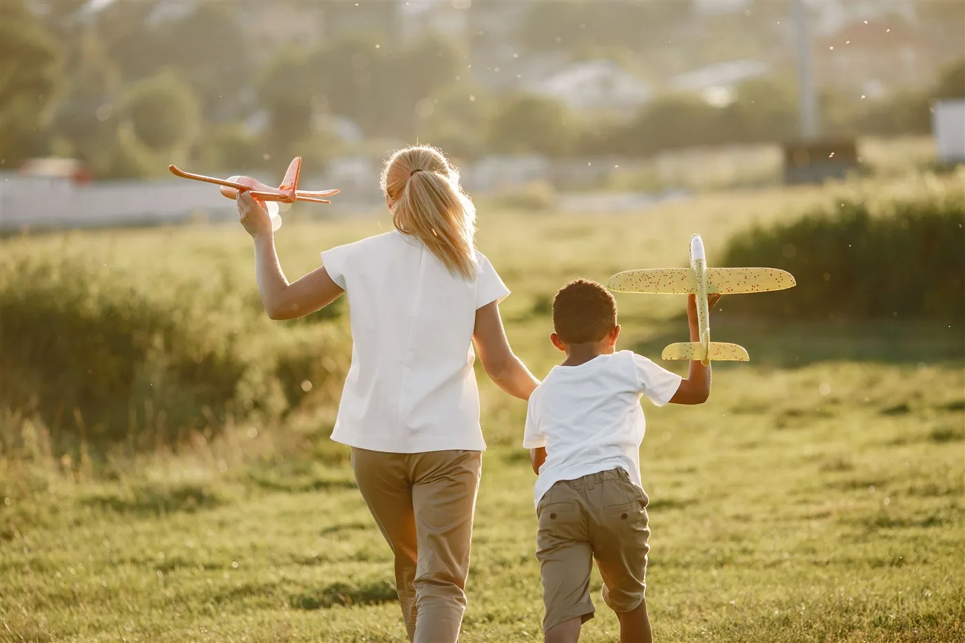 Mulher e criança caminhando em um campo, brincando com aviões de brinquedo, representando o dia a dia do programa au pair nos Estados Unidos