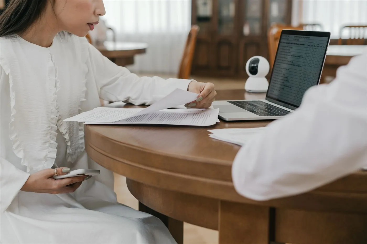 Mulher revisando documentos impressos ao lado de um notebook, representando a preparação da papelada exigida para o intercâmbio nos Estados Unidos