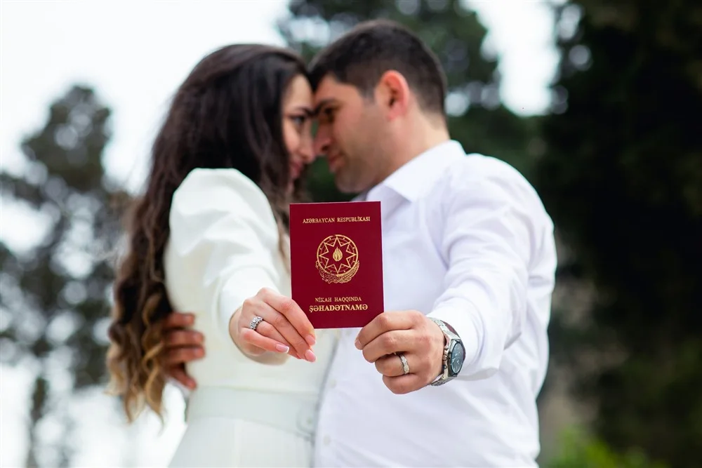 Casal segurando a certidão de casamento ao ar livre