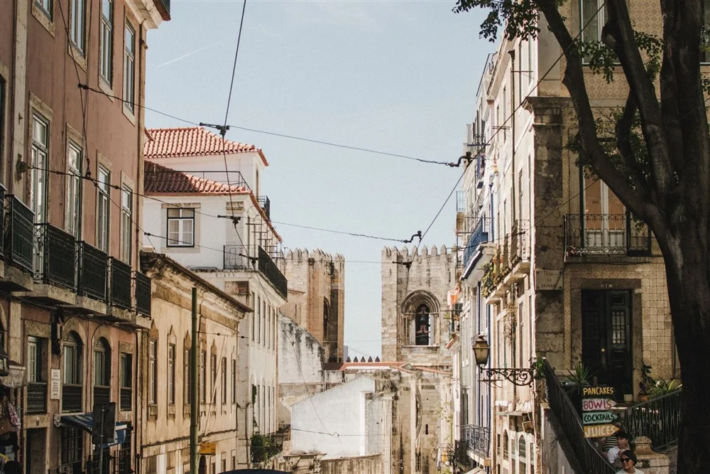 Rua histórica de Lisboa com bondinho amarelo e pessoas caminhando