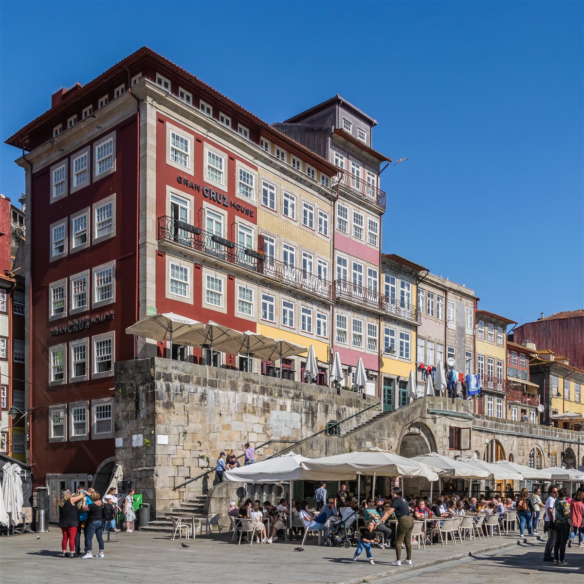 Cais da Ribeira, no Porto, Portugal, com prédios coloridos e mesas de restaurante ao ar livre