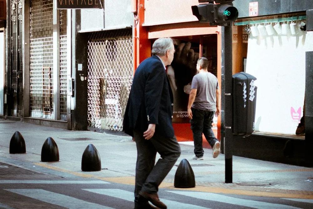 Pedestres atravessando uma rua do centro de Buenos Aires, com lojas e prédios ao fundo